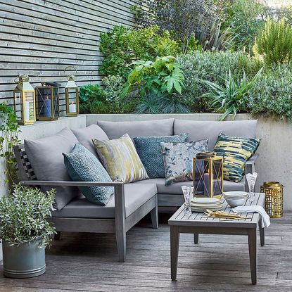 garden area with candle lantern and sofa with cushions and plant on pot