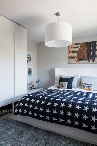 a modern bedroom with white walls and a statement star blanket