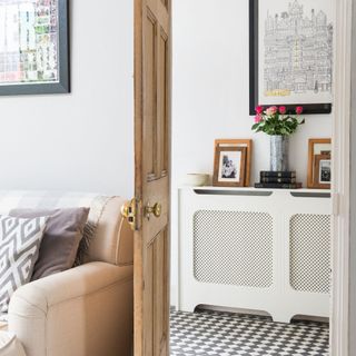 Looking out of living room door into a hallway with checkered tiles and a white radiator cover