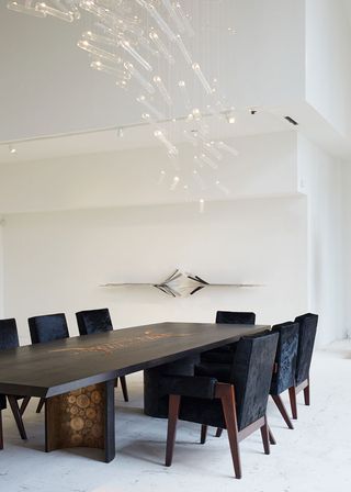 A chandelier by Studio Drift hangs above a dining table