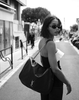 Laura Harrier carrying a large black Saint Laurent Jamie 4.3 Bag and wearing a black dress