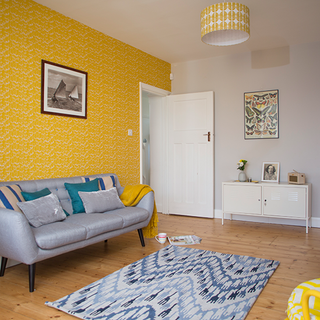 living area with yellow wallpaper and wooden flooring