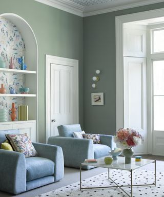 pale green living room with sky blue armchairs, rug, metal and marble coffee table, alcove with wallpaper, wallpaper on ceiling