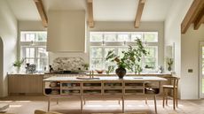A Coastal Scandinavian kitchen with wooden cabinetry, warm white walls, and high ceilings