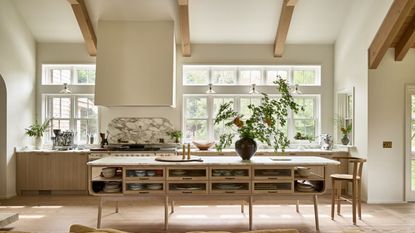 A Coastal Scandinavian kitchen with wooden cabinetry, warm white walls, and high ceilings