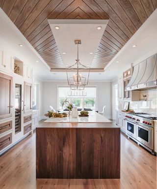 A large kitchen with a wooden island and a wooden paneled ceiling