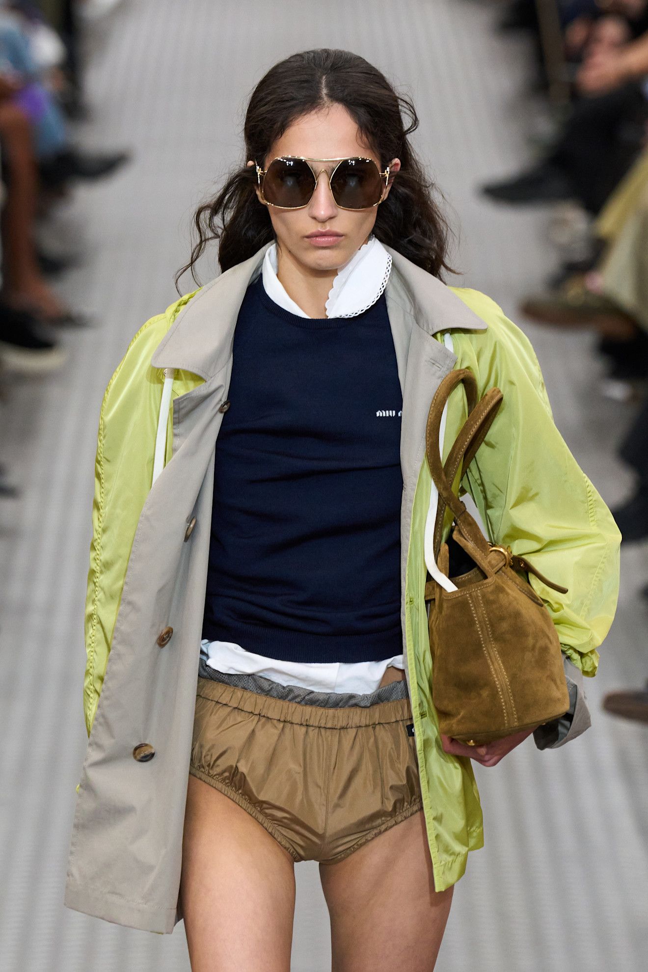 Woman on Miu Miu runway in anorak and sweater.