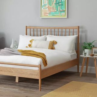 A wooden spindle back bed frame in a bedroom