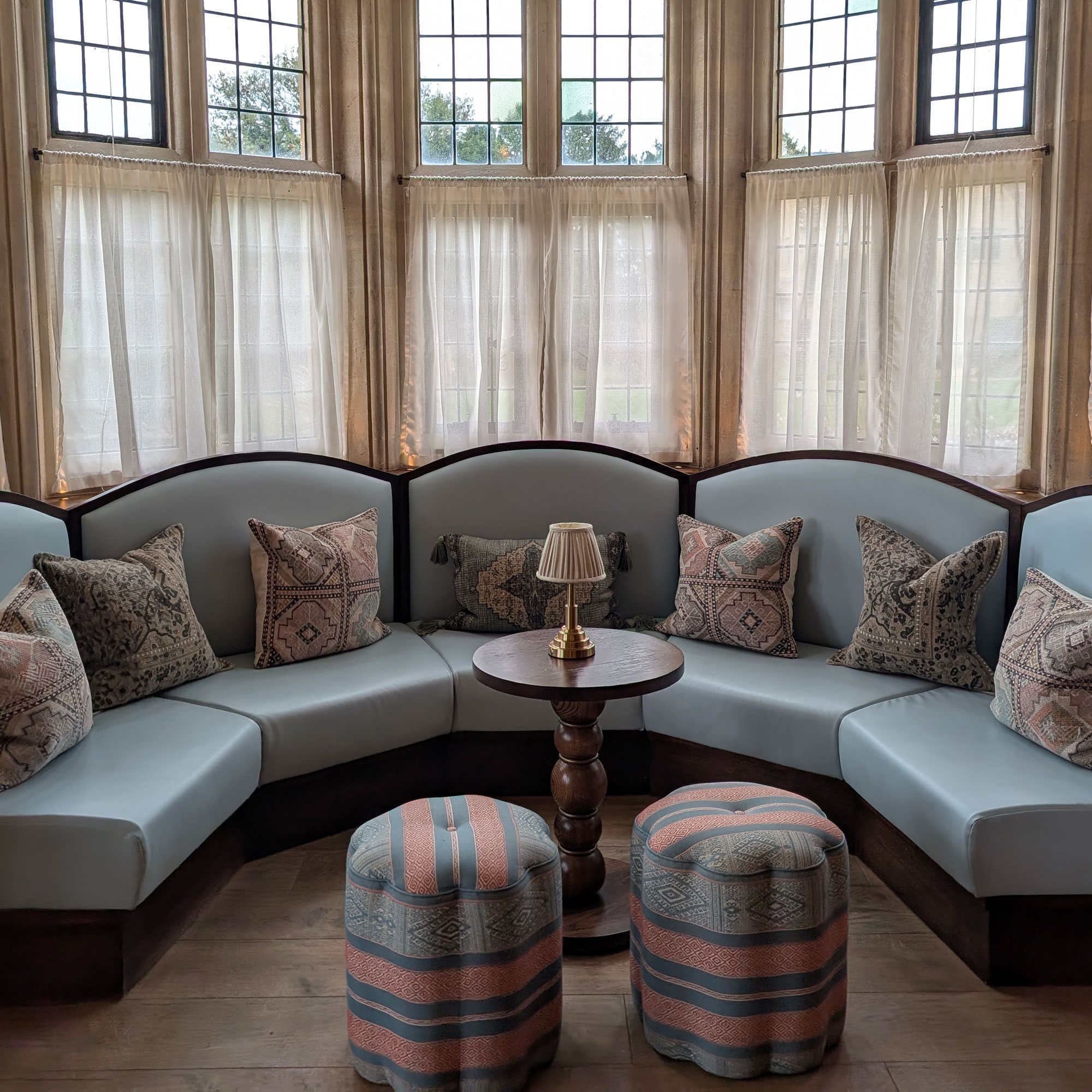 Curved banquette seating in bay window area with cafe curtains