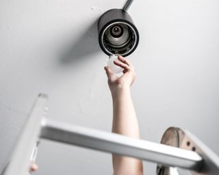 Man on ladder changing lightbulb