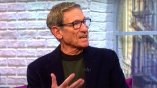 Maury with glasses and a dark shirt talking on his talk show.