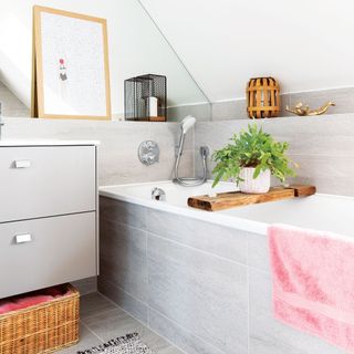 Bathroom with grey marble tiles, vanity unit with drawers, shower bath, pink towel, lantern