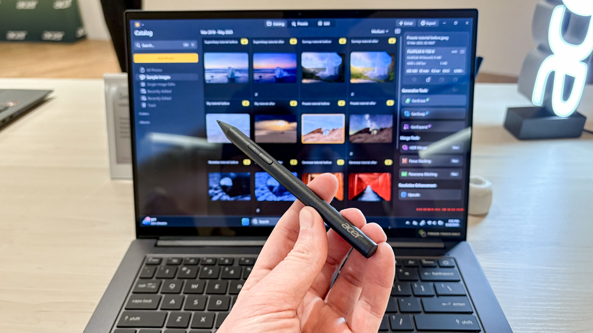 Hand holding Acer Stylus pen with Acer Swift X 14 on table in background