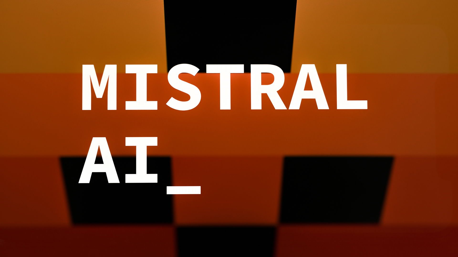 Mistral logo and branding pictured against a multi-colored black, orange, and yellow background.