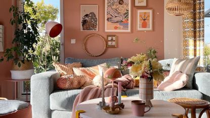 An apartment with a pink wall, blue sofa, and decorated coffee table