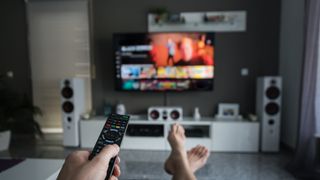 A person sits in their living room accessing a TV streaming site