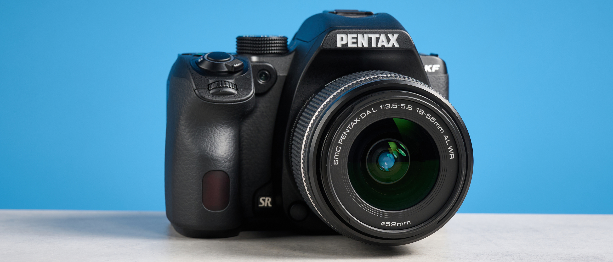Pentax KF DSLR camera photographed on a blue background