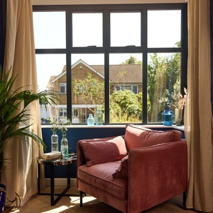 Living room with terracotta armchair and large aluminium framed window above