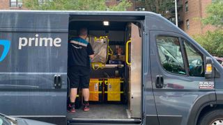 Amazon Prime delivery person in van sorting packages, Queens, New York.