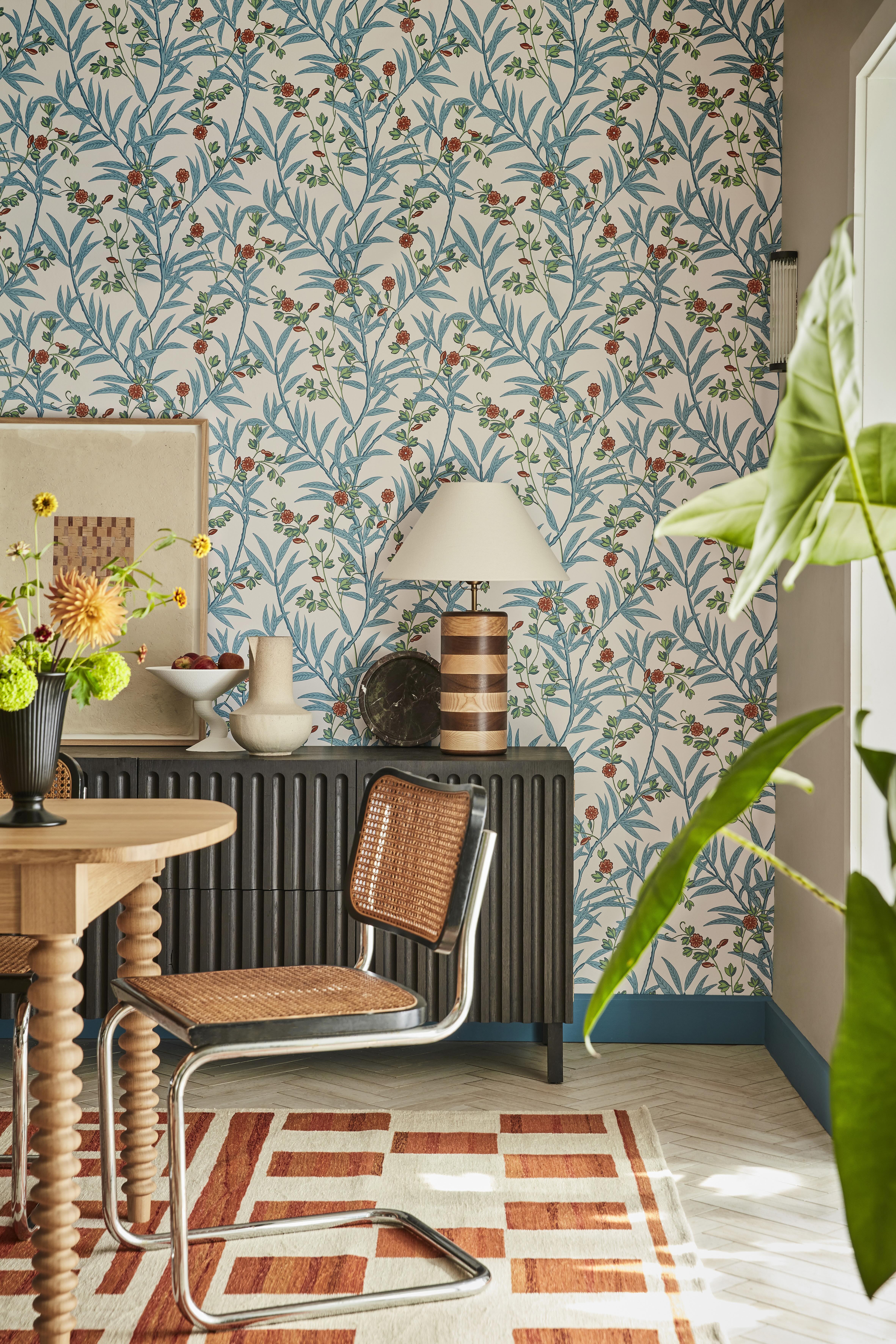 Blue painted baseboards in a dining room with blue botanical wallpaper