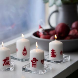 IKEA's Vinterfint white block candles with red Christmas motifs on a windowsill