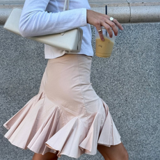 woman wearing pink skirt and white long sleeve t-shirt holding iced coffee