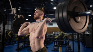 Male performing barbell jerk in gym