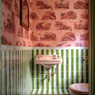 Bathroom with pink wallpaper and green and white tiles