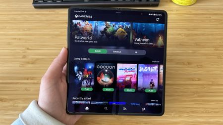 Honor Magic V2 unfolded in reviewer's hand against a wooden desk