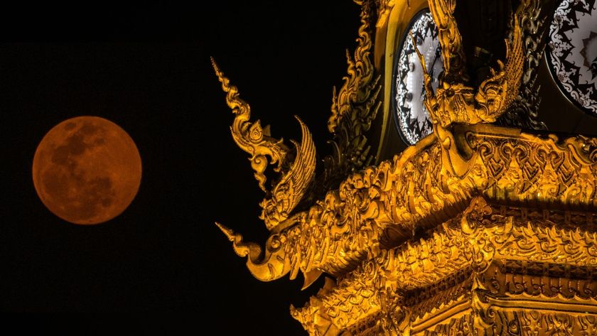 Photo of a red moon and the golden clock tower of Chiang Rai province the northern part of Thailand.