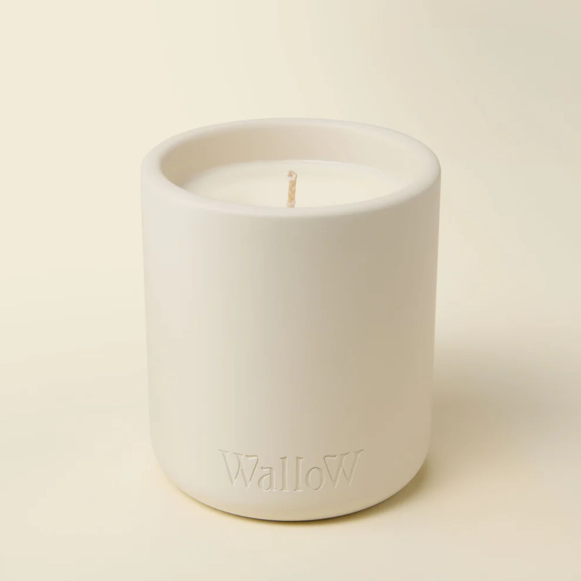 White candle with subtle Wallow branding