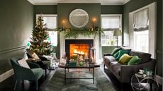 Christmas living room with green walls. Garland on the mantelpiece and Christmas tree in the corner