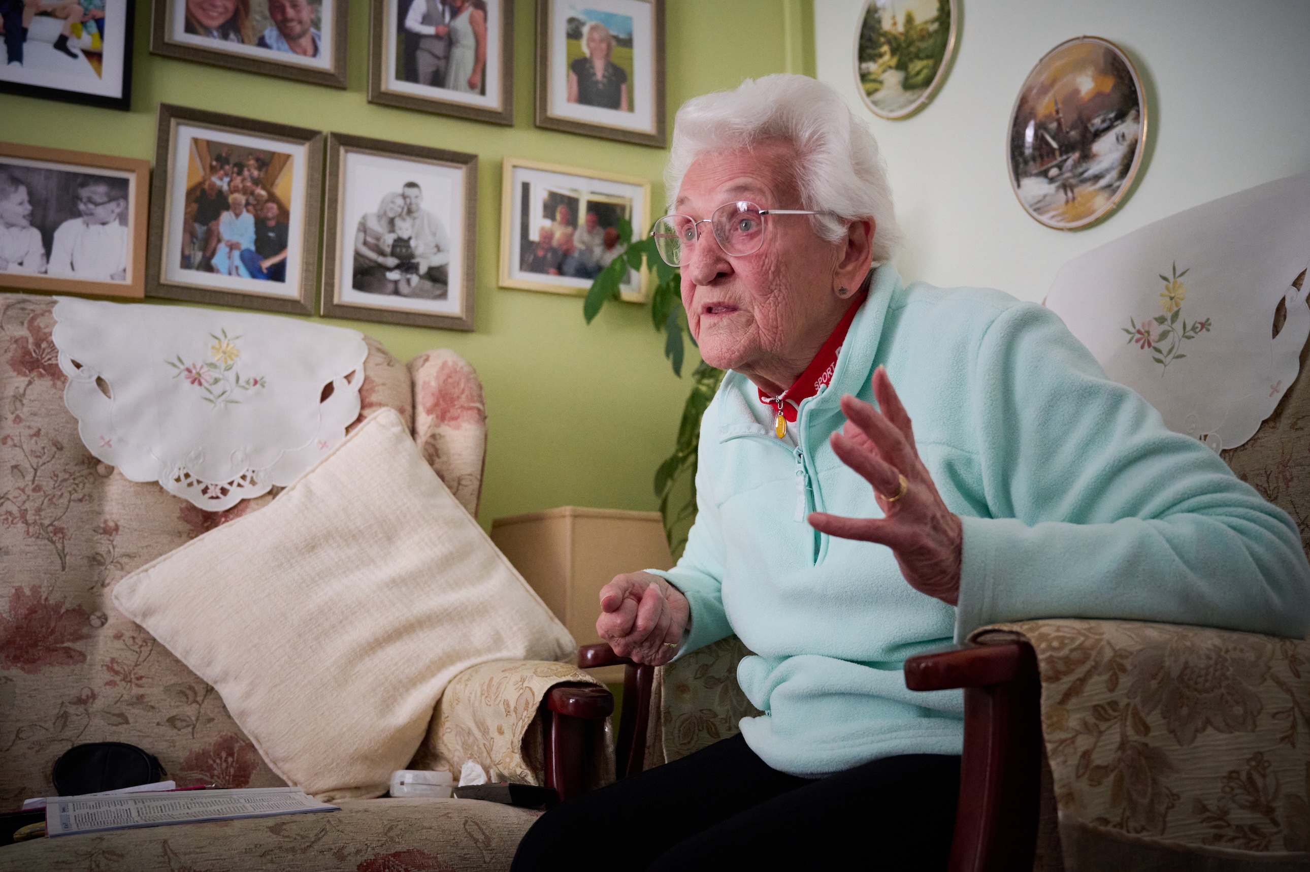 Shirley Hockridge seated at home in from of a wall of family photos