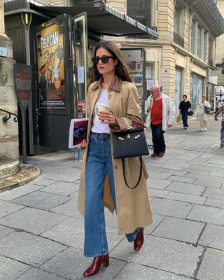 A French woman wearing a trench coat and jeans