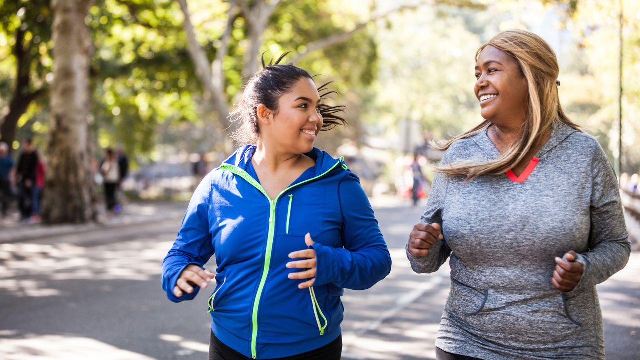 Two plus size women jogging in Central Park, New York during a beautiful day.