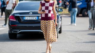 street style shot of person in check vest and patterned midi skirt