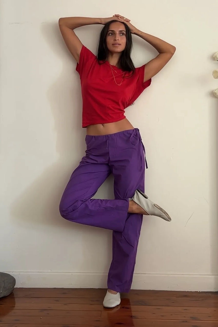 A woman wearing a red T-shirt and purple pants