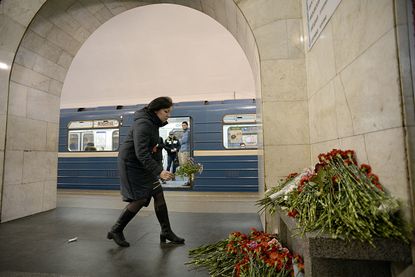 A mourner leaves flowers at a makeshift memorial for the deadly St. Petersburg attack.
