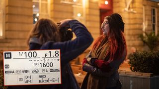 Photographer photographing a portrait of a model at night with an inset image of a Nikon camera's settings screen