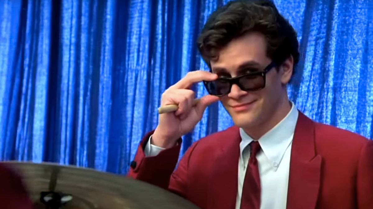 Tom Everett Scott smiles while adjusting his sunglasses in That Thing You Do.