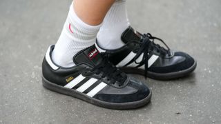 Natalia Verza wears white socks, black leather and suede Samba sneakers from Adidas on October 18, 2022 in Paris, France.