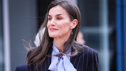 Queen Letizia of Spain, wearing a pinstripe suit and lilac top, smiles as she arrives to attend a meeting at UNICEF headquarters on March 19, 2025