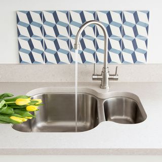 kitchen sink on white countertop with geometric tiles on white wall