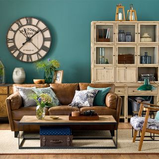living area with blue wall and brown sofa and wall clock and cabinet
