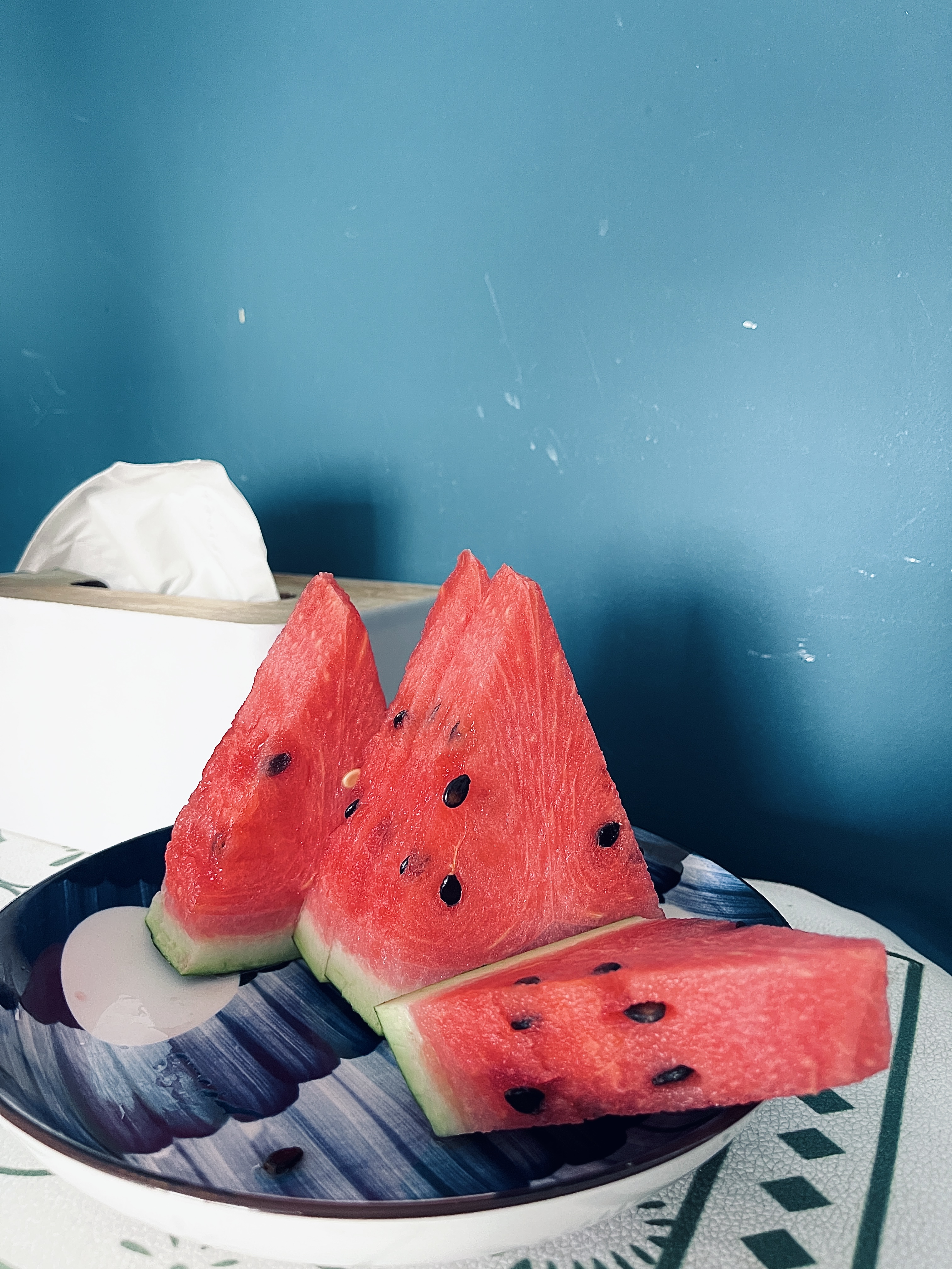 Four slices of watermelon in a bowl in front of a blue wall