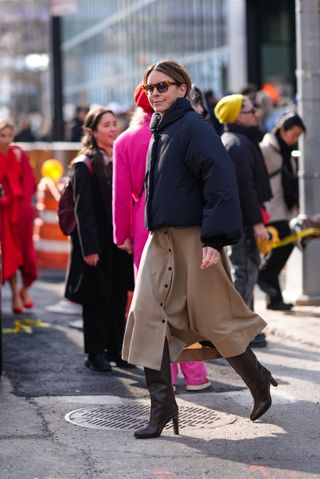 Woman in puffer jacket, skirt, and boots