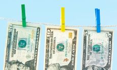 twenty, ten, and five dollar bill held up with colorful clothespins against a light blue background