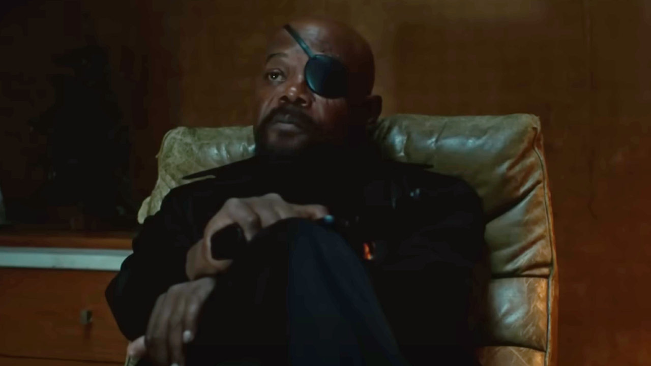Samuel L. Jackson sitting, holding a pistol in Spider-Man: Far From Home
