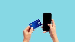 Woman hand holding blue credit card and using smart phone isolated on blue background, front side view. 