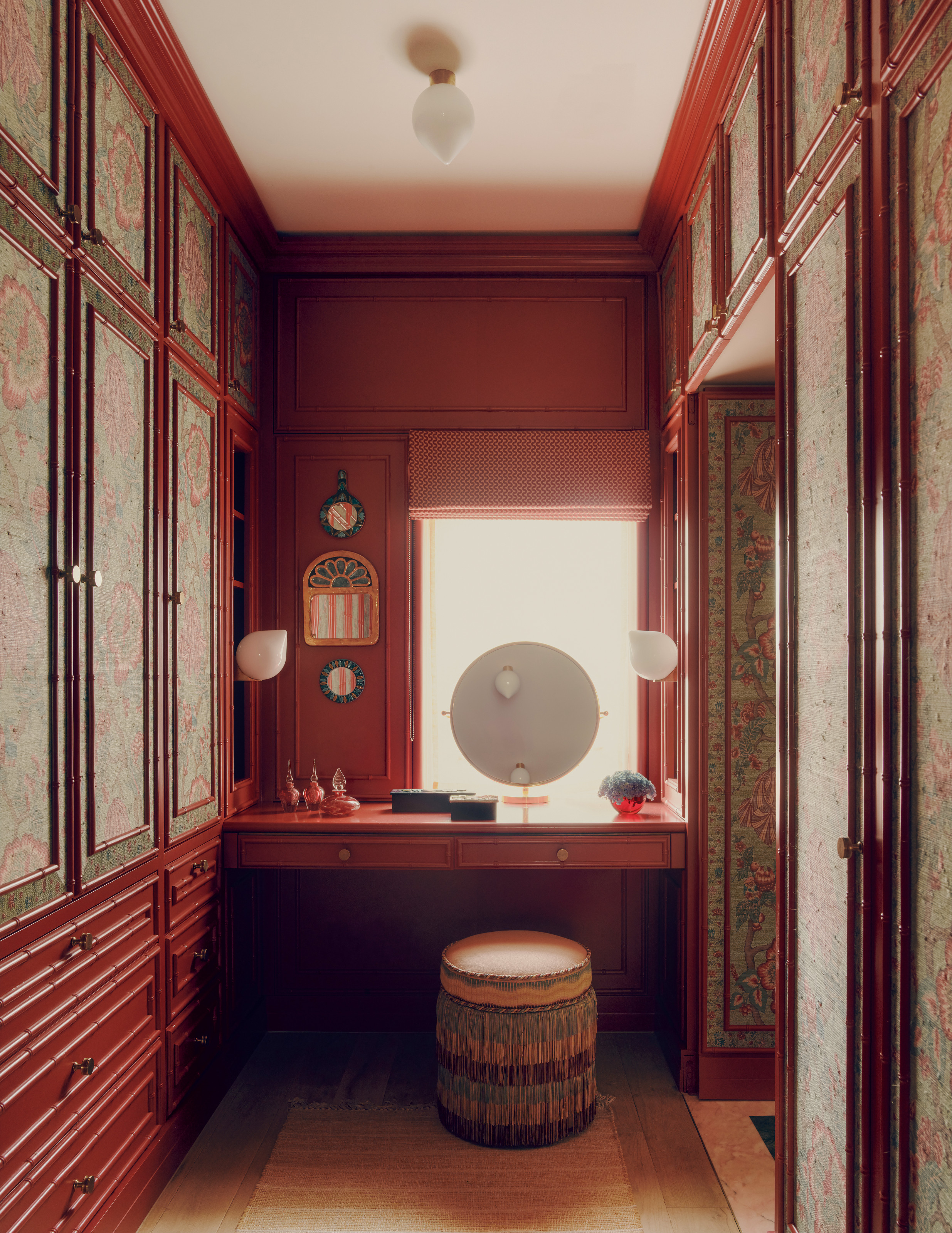 Red dressing area with built-in wardrobe and dressing table with fringed stool